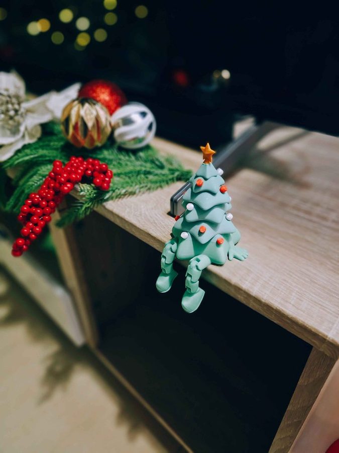 A small green articulated 3D printed tree figure with movable legs, the kind used as a novelty party giveaway.