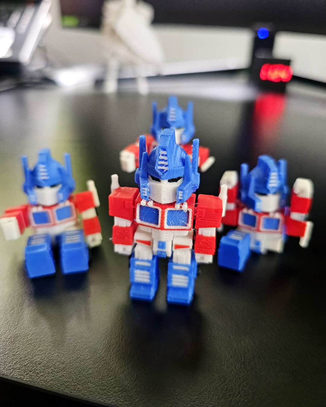 A red, white and blue 3D printed robot figure standing upright, printed in several colors in one piece.