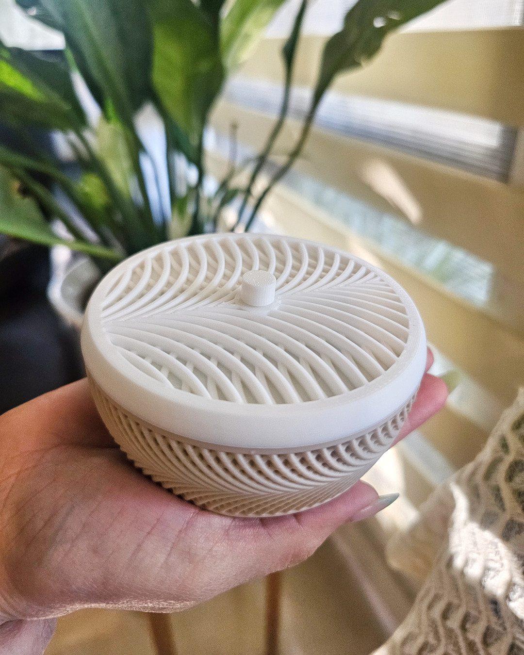 A white ribbed 3D printed decor piece held in one hand, showing the print lines and the size against a palm.